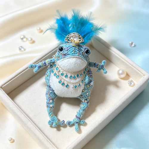 Blue Feather Royal Toad – Hand-Knitted Figurine with Blue Feather Crown, Gold Tiara, Layered Crystal Chains, Pearl Bracelet &amp; Diamond Accents | The Third Space