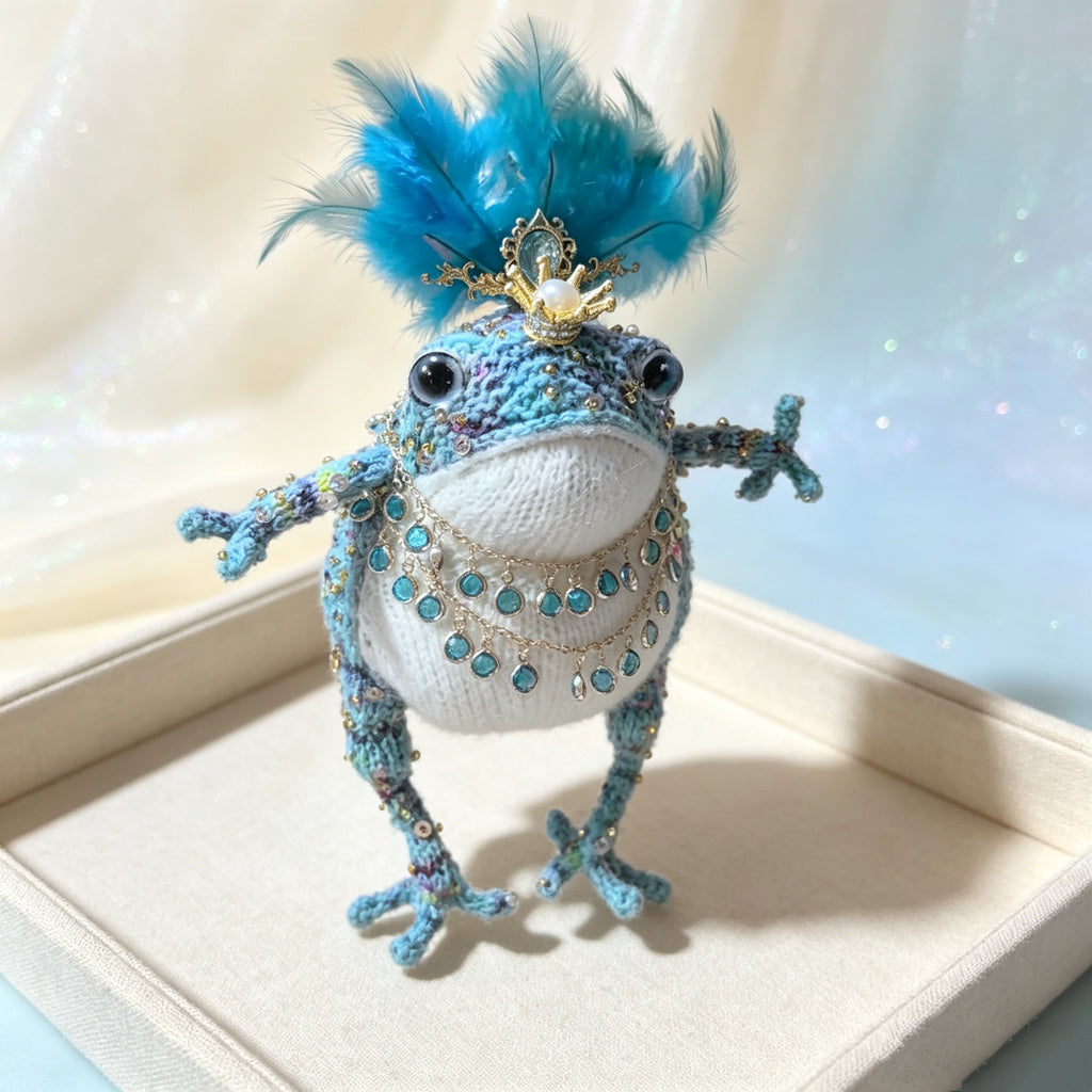 Blue Feather Royal Toad – Hand-Knitted Figurine with Blue Feather Crown, Gold Tiara, Layered Crystal Chains, Pearl Bracelet &amp; Diamond Accents | The Third Space